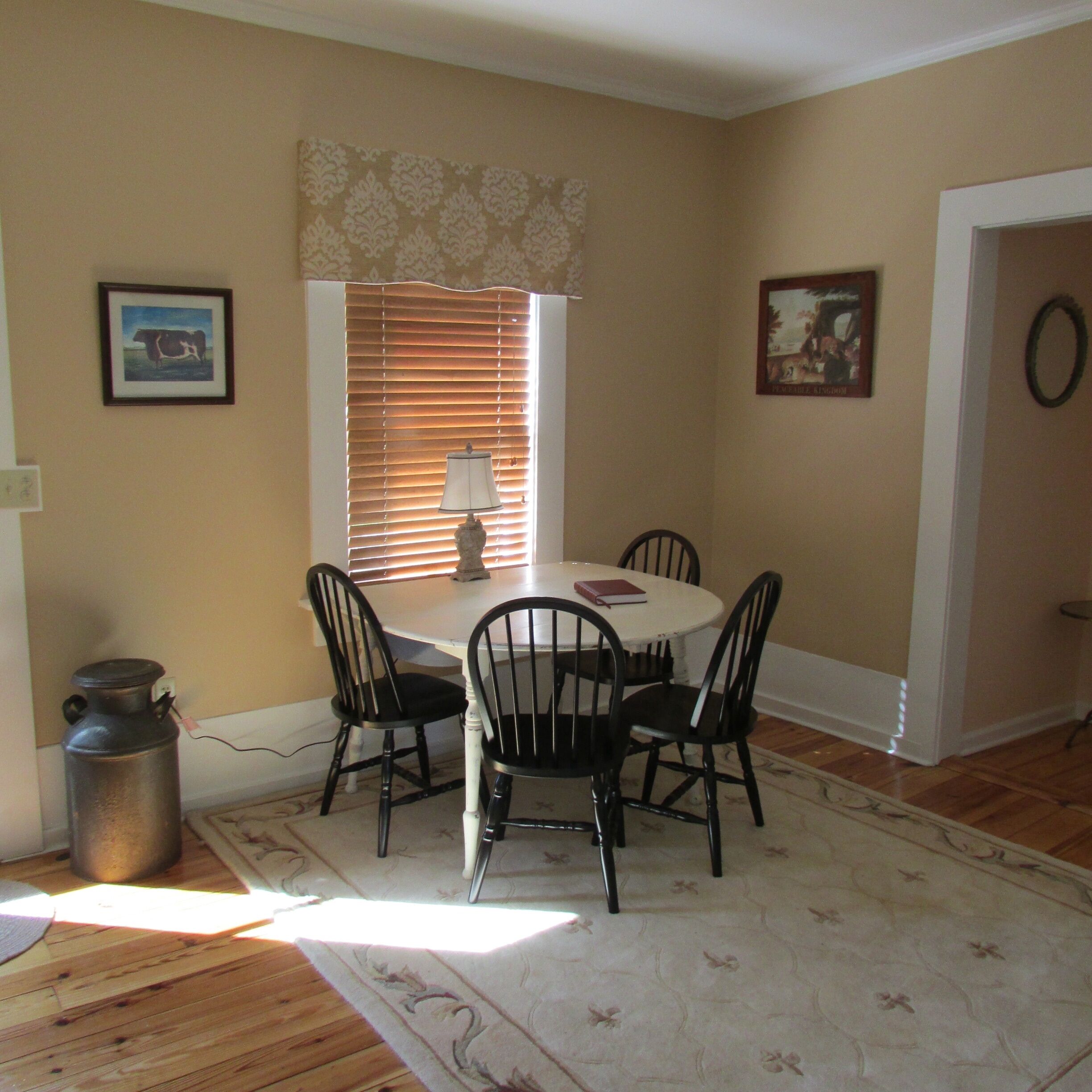 A dining area with a table and chairs, a window with blinds, and a radiator.
