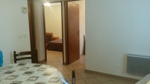 A bedroom with a bed, a wooden door, and a tiled floor.
