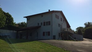 A two-story building with a sloped roof, a covered porch, and a staircase leading to a balcony.