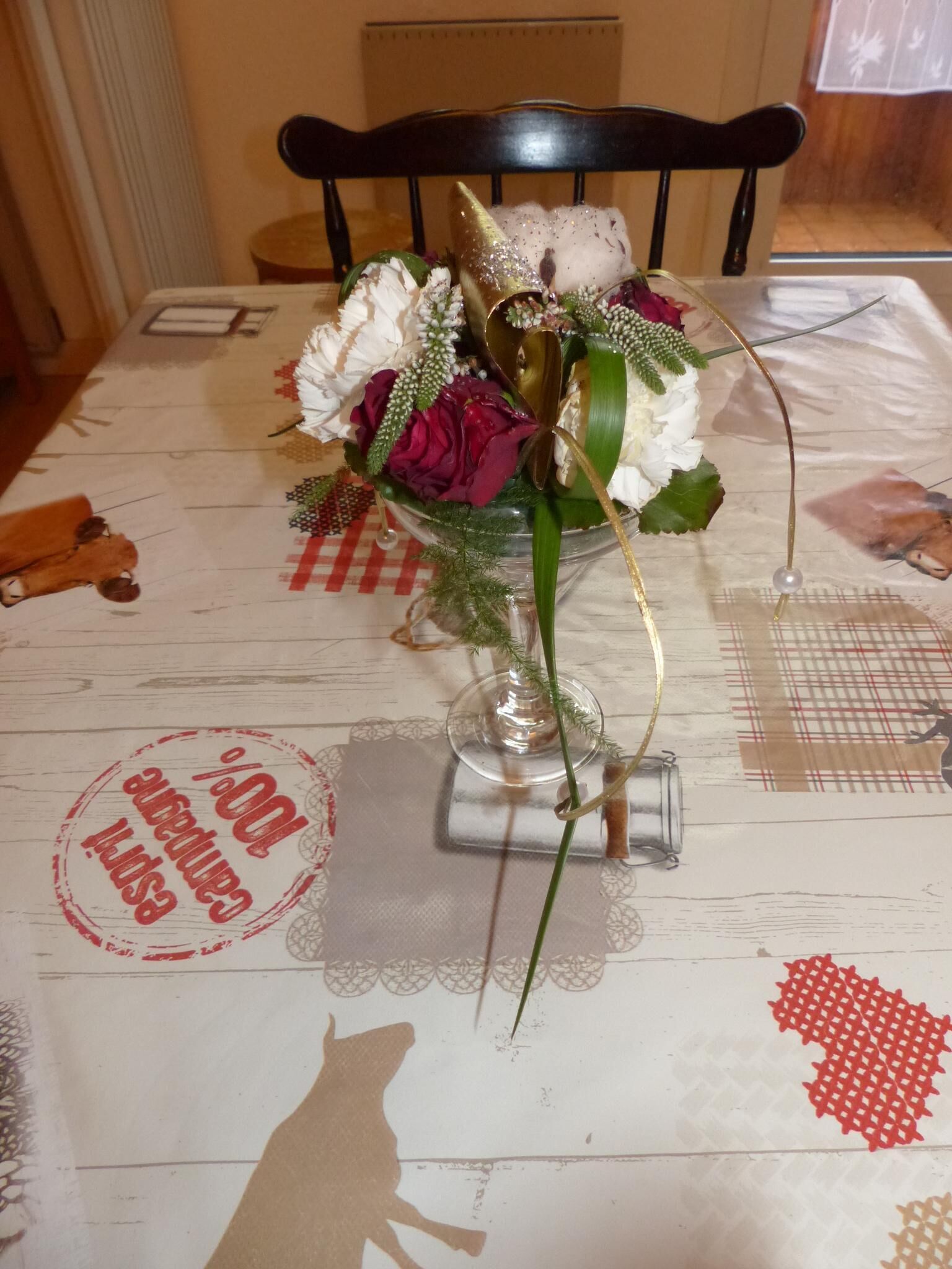 Una mesa con un centro de mesa floral, un florero de vidrio y un mantel individual con un diseño de corazón.