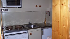 Une cuisine compacte équipée d’un four à micro-ondes, d’une cuisinière, d’un évier et d’un lave-vaisselle.