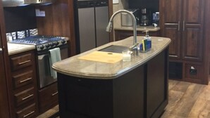 A kitchen with dark wooden cabinets, stainless steel appliances, a central island with a sink, and pendant lighting. - RELAX OFF THE BEATEN PATH! (Terlingua)