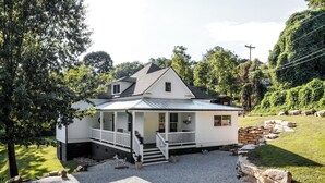Une maison à deux étages avec un porche, un mur en pierre et une allée gravillonnée.