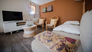 A modern room with a flat-screen TV, two wicker chairs, a sofa, and a small round table. - Cottage between Bordeaux and St Emilion with Magnificent Park, surrounded by Vines (Génissac)