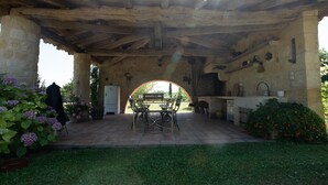 An outdoor patio with a stone table and chairs, surrounded by potted plants and a stone wall. - Cottage between Bordeaux and St Emilion with Magnificent Park, surrounded by Vines (Génissac)