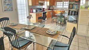 A modern kitchen with wooden cabinets, a dining area with a glass table, and a bookshelf with books. -  PARADISE/ ask discount Sept/Oct- bonefishing, beaches/town/360 view, 98 5 stars (Georgetown)
