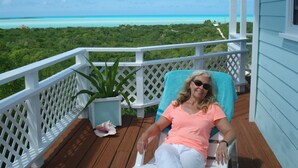 A woman sitting on a deck chair with a view of the ocean and greenery. -  PARADISE/ ask discount Sept/Oct- bonefishing, beaches/town/360 view, 98 5 stars (Georgetown)