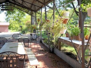An outdoor patio with metal tables and chairs, surrounded by potted plants and a wooden fence. - Paradise in the Little Buffalo River Valley less than a mile from Jasper. (Jasper)