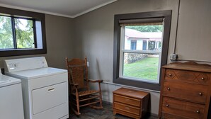 Une buanderie équipée d’un lave-linge, d’une chaise en bois, d’une petite commode en bois et d’une commode à tiroirs.