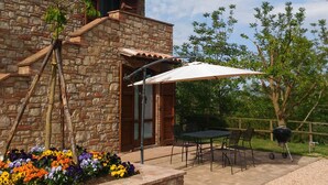 A stone building with a patio area featuring a table and chairs, surrounded by a gravel driveway and a flower bed. - 10 minutes walk from Todi center, with pool (Todi)