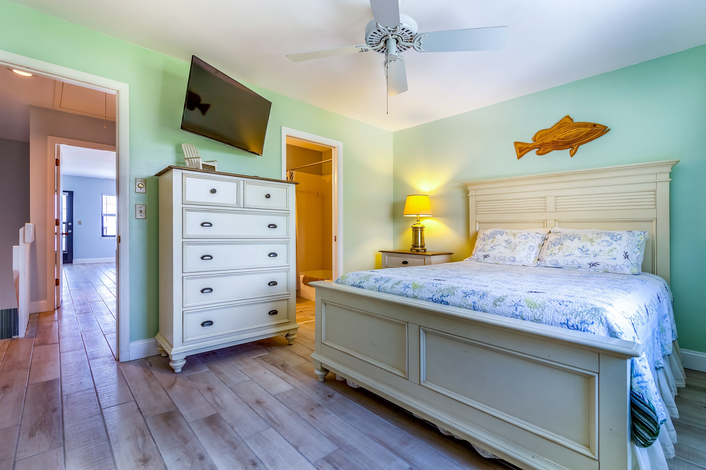 Une chambre à coucher avec un lit, une commode et un ventilateur de plafond.