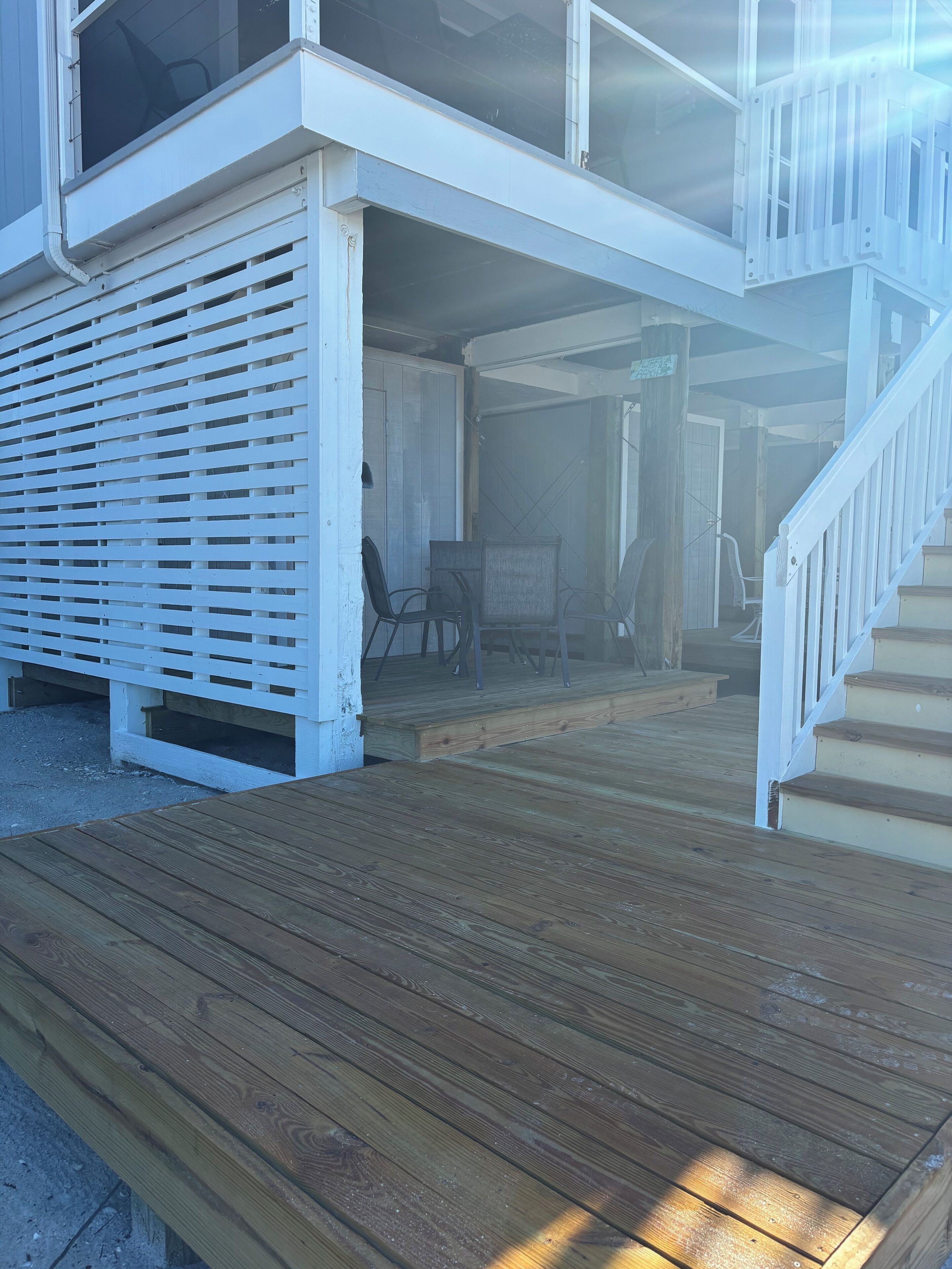 A wooden deck leading to a covered outdoor area with a staircase.
