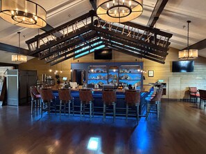 A bar area with a high ceiling, wooden beams, and a bar counter with stools.