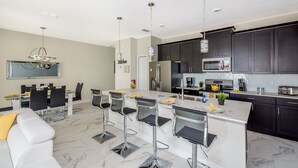 Una cocina moderna con armarios oscuros, electrodomésticos de acero inoxidable y una isla central con taburetes de bar.