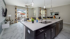 Una cocina moderna con una isla grande, gabinetes negros y un ventilador de techo.