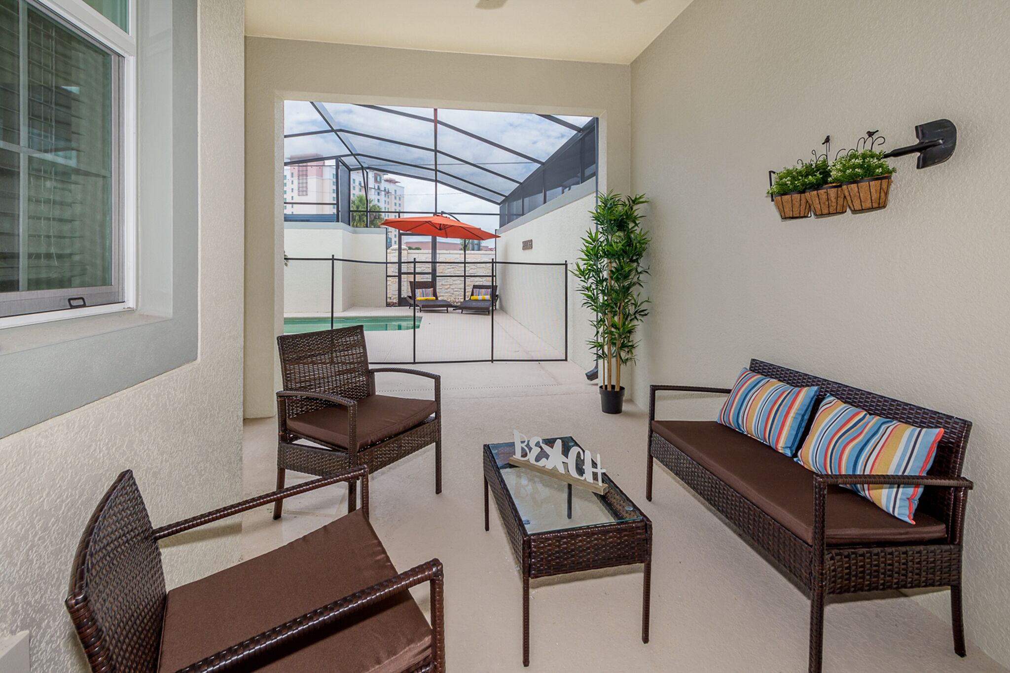 Ein modernes Wohnzimmer mit Rattanmöbeln, einem Glastisch und einer Couch mit gestreiften Kissen.