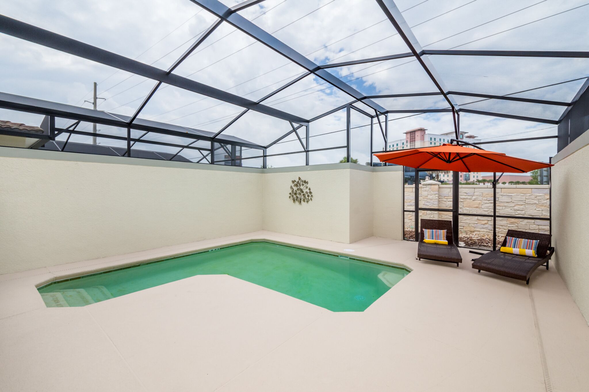 Ein Hallenbad mit Glasdach, zwei Liegestühle und einem roten Sonnenschirm.
