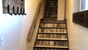 A wooden staircase with a handrail, a wall-mounted coat rack, and a light switch. - Bridger View - Studio (Gallatin County)