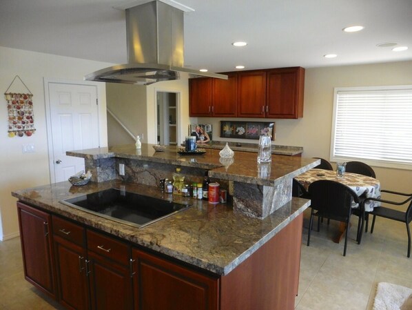 Una cocina con encimeras de granito, armarios de madera y una campana extractora de acero inoxidable.