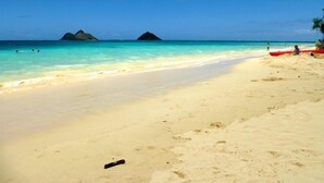 Una platja amb aigua turquesa cristal·lina, sorra daurada i dues illes petites a la distància.