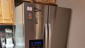 A stainless steel refrigerator with a water dispenser and a digital control panel.