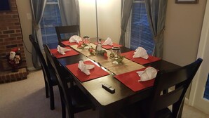 A dining table set with red placemats, white napkins, and a centerpiece.