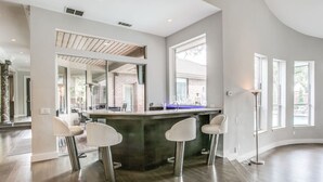 A modern kitchen with a bar area, large windows, and a high ceiling. - The Best Dallas Has To Offer. Heated Pool/Spa! (Dallas)