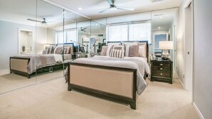 A bedroom with a large bed, a nightstand, a mirror, and a ceiling fan. - The Best Dallas Has To Offer. Heated Pool/Spa! (Dallas)