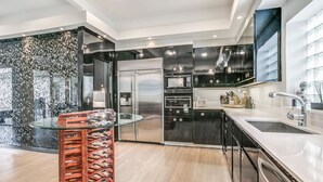 A modern kitchen with stainless steel appliances, a glass-top dining table, and black cabinetry. - The Best Dallas Has To Offer. Heated Pool/Spa! (Dallas)