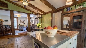 Una cocina con isla central, vigas de madera y pared verde.