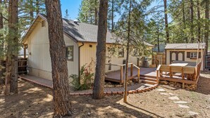 Une cabane dotée d’une terrasse en bois, entourée de grands pins.