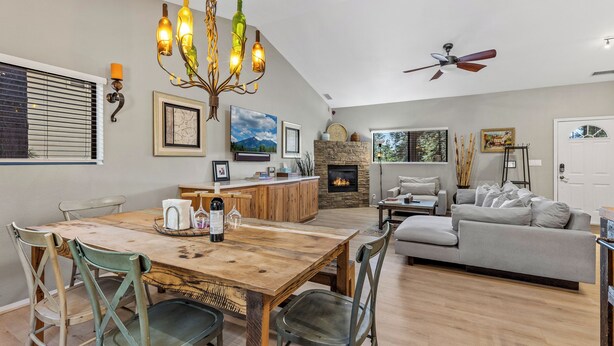 Un vaste espace de vie comprenant une table à manger en bois, une cheminée, un canapé et un ventilateur de plafond.