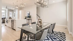 Een moderne keuken met een centraal eiland, roestvrijstalen apparatuur en hanglampen.