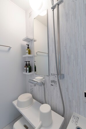 Et moderne badeværelse med et hvidt toiletbord, et spejl og en bruseplads.
