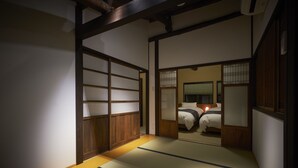 A traditional Japanese room with tatami flooring, sliding doors, and a bed with white bedding.