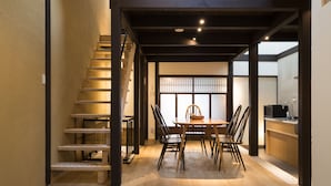 A modern interior with a wooden staircase, a dining area with a table and chairs, and a kitchen area.