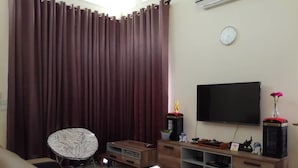 A living room with a sofa, a zebra-patterned chair, a TV, a wooden cabinet, and a curtain. - KKP Homestay Alor Setar (Alor Setar)