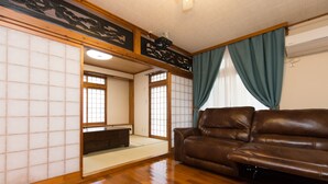 Una tradizionale stanza giapponese con pavimenti in tatami, un divano in pelle marrone e pannelli scorrevoli shoji.