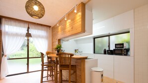 Una cucina moderna con mobili in legno, un'area pranzo con sedie, un'ampia finestra e un cestino.