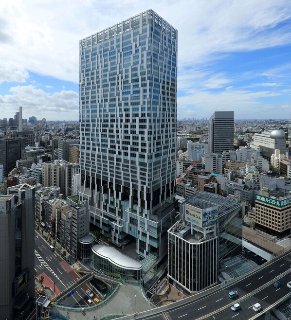A high-rise building with a grid-like facade, surrounded by other urban structures.