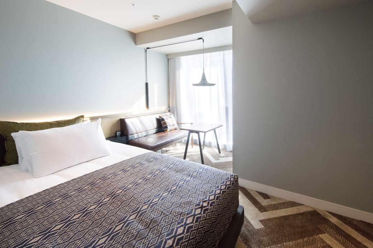 A hotel room with a large bed, a desk, and a chair.