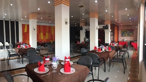 Un restaurante con varias mesas dispuestas para comer, con servilletas rojas y platos blancos.