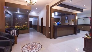 Un vestíbulo de hotel con mostrador de recepción, zona de estar y un diseño decorativo en el suelo.