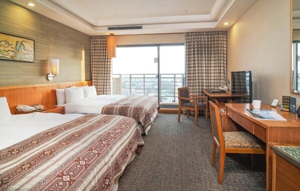 Habitación de hotel con dos camas, un escritorio, una silla, un televisor y una ventana con cortinas.