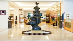Una estatua en un vestíbulo con piso pulido, un mostrador de recepción y diversas obras de arte expuestas.