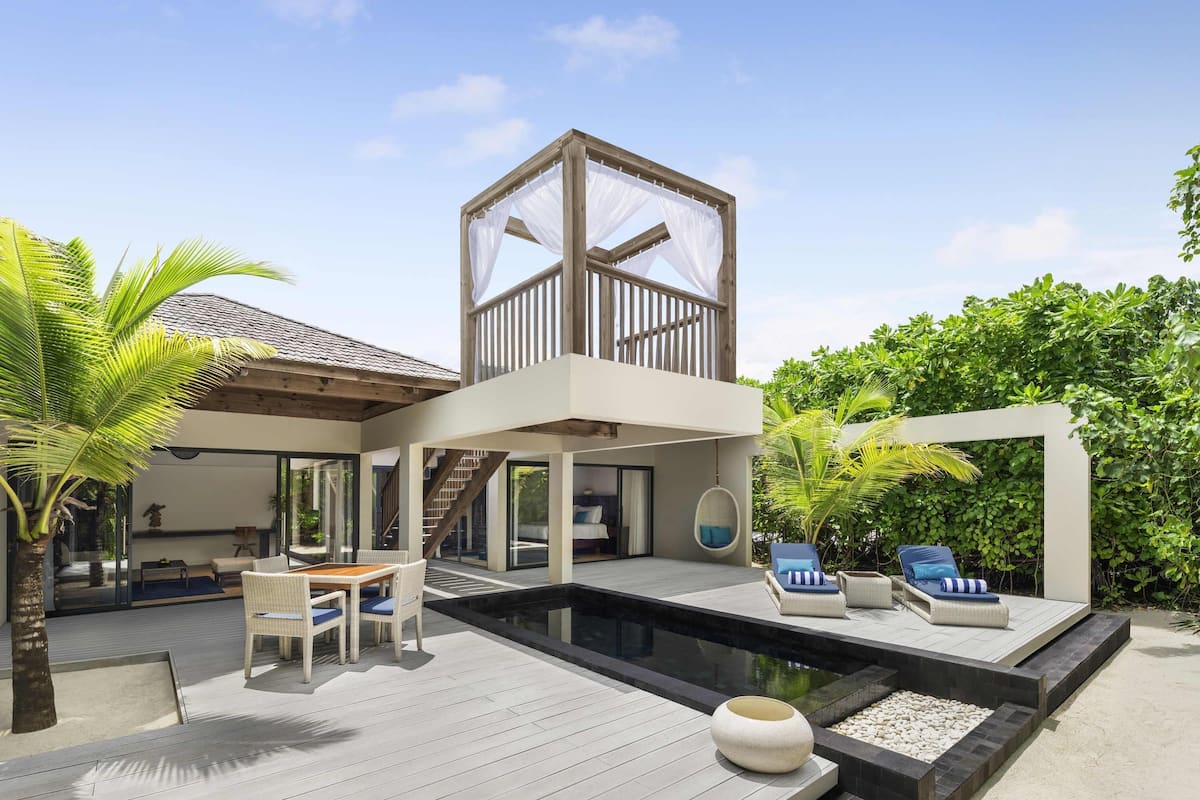 A modern house with a pool, outdoor furniture, and lush greenery.