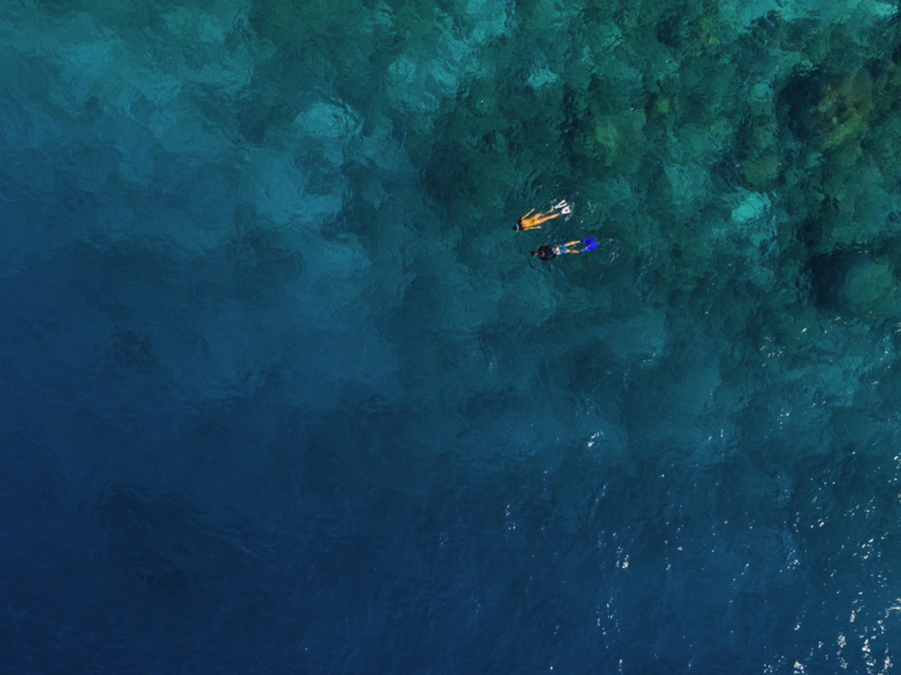 An aerial view of a clear blue sea with two boats.