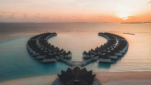 Un resort sobre el agua con una distribución circular de bungalows unidos por pasarelas.
