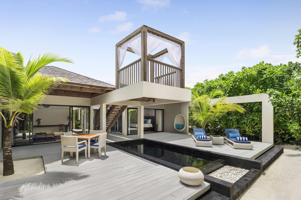 A modern house with a pool, outdoor furniture, and lush greenery.