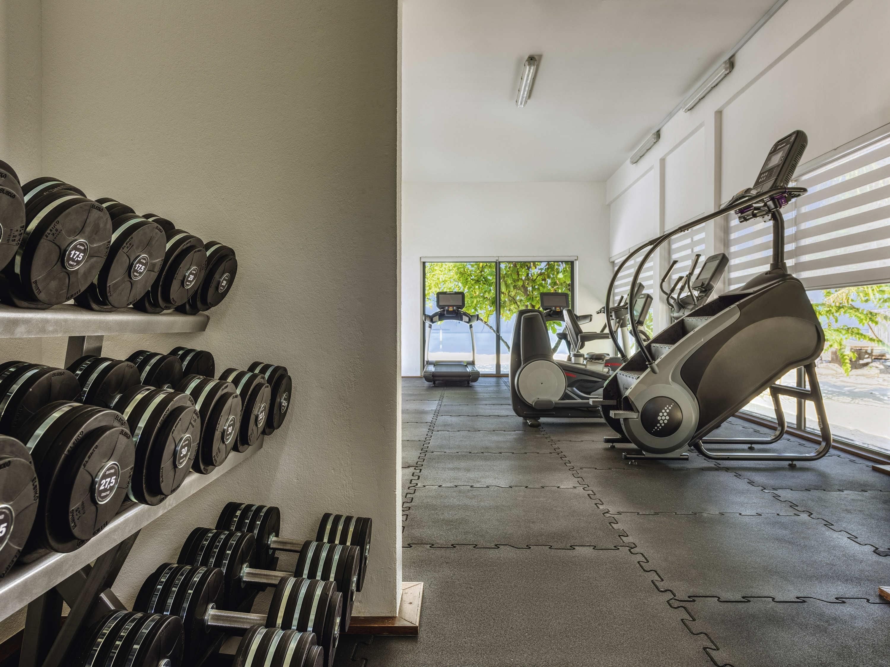 A gym with weight racks, treadmills, and elliptical machines.